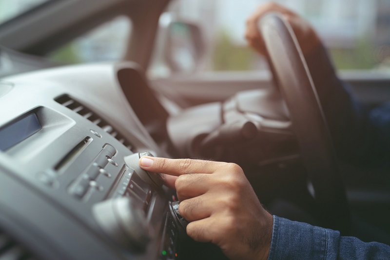 Driver turns volume dial on car radio
