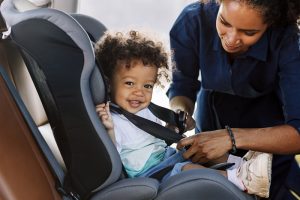 Parent strapping child into car seat.