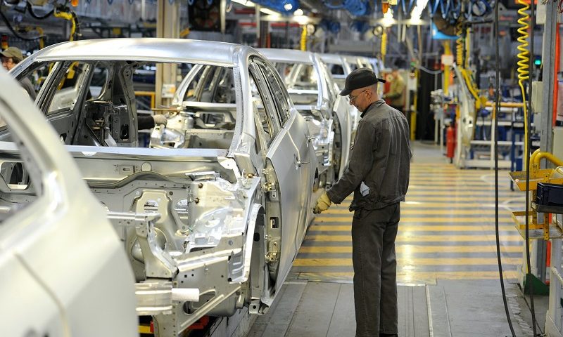 Man inspects car on production line in factory