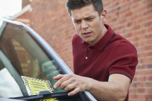 A male driver looks at a parking ticket.