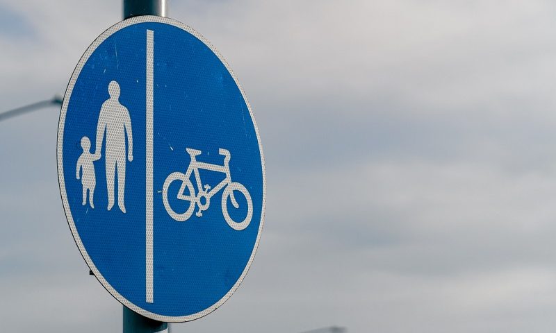 A road sign with images of pedestrians and a bike