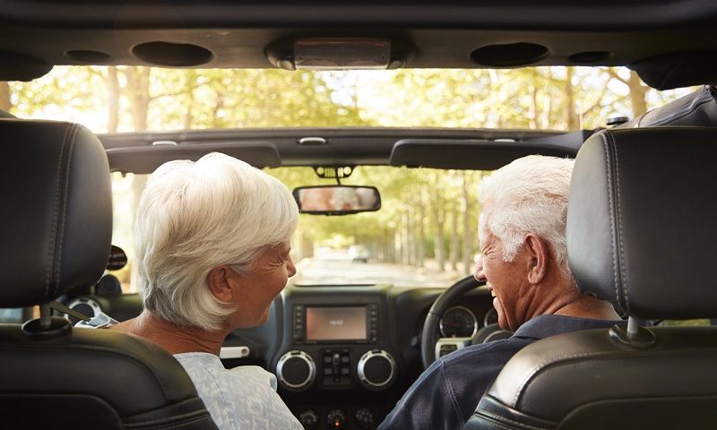 Older couple driving in open-top car