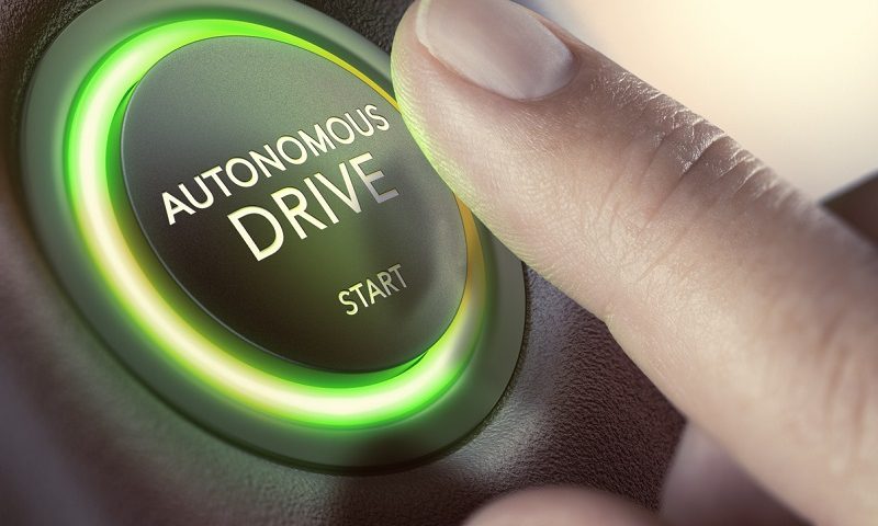 A finger pressing a button to start a self-driving car