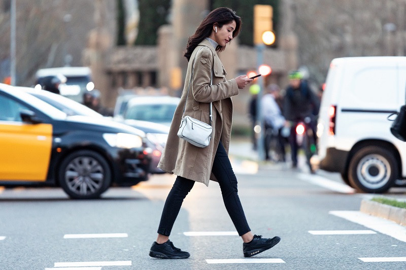 A woman crossing the road while using her phone