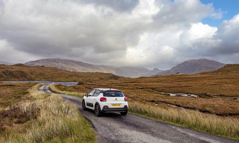 Car driving on a rural road in the Scottish Highlands