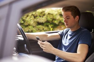 A young man uses a mobile phone while driving.