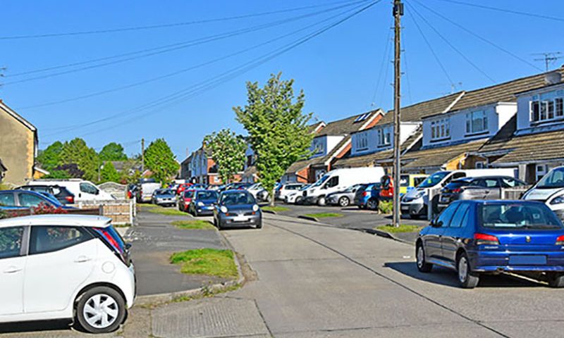 Street scene row semi detached houses paving over front garden with paved driveway replacing house lawn for some car parking space Essex England UK