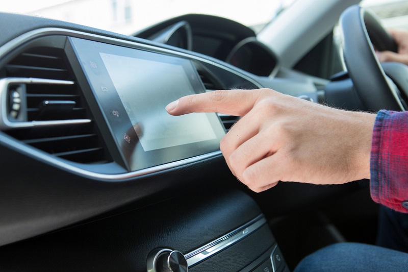 Man’s hand clicking on touch screen in car