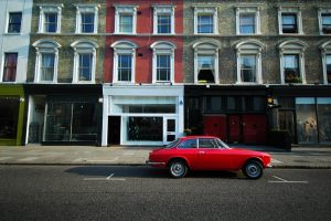 Old red sport car parked in front of a building in Notting Hill, London.