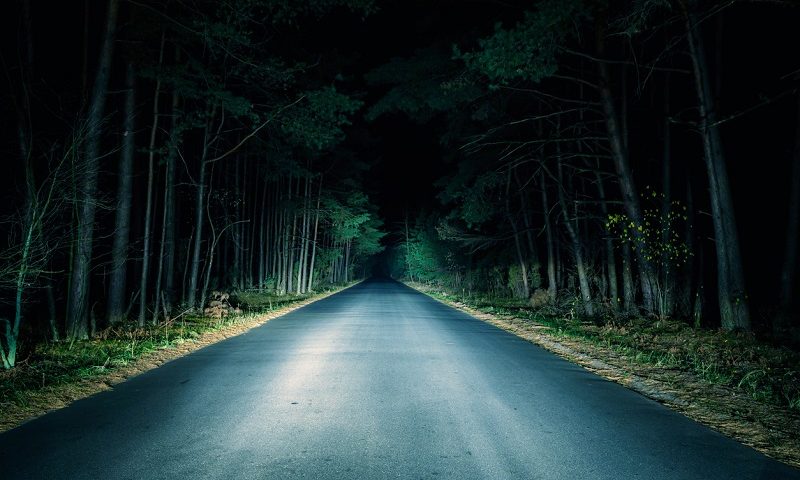 Empty country road illuminated by headlights