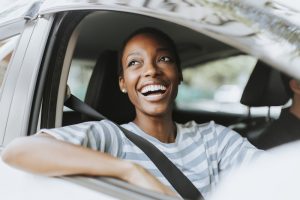 Woman smiling while driving a silver car
