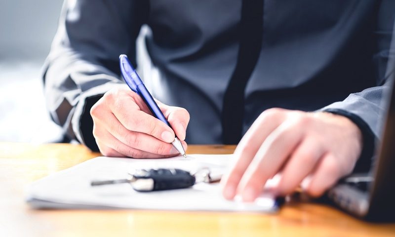 Man signing documents when buying a new car.