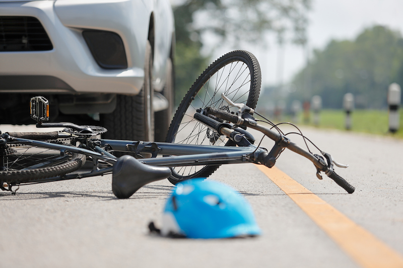 A bike lying in the road after having been hit by a car